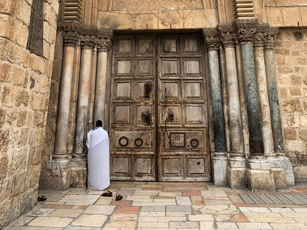 A worshiper prays outside the Church of the Holy Sepulchre, the traditional site of Jesus' tomb. Its wooden doors are shut now to deter the spread of COVID-19, and only clergy may perform the daily prayer rituals inside.