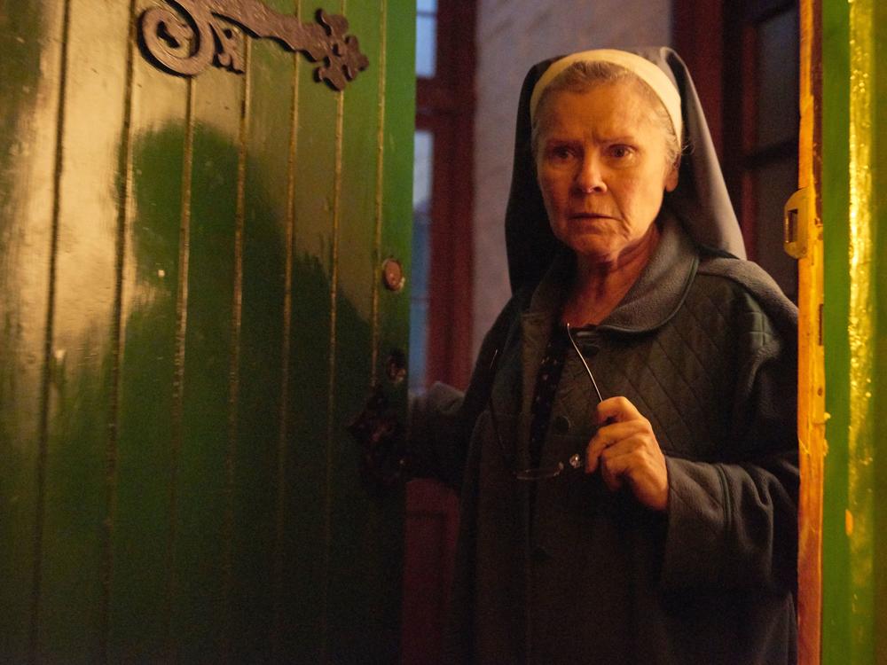 A mischievous nun (Imelda Staunton) welcomes a stranger into a decrepit house in the supernatural thriller <em>Amulet</em>.
