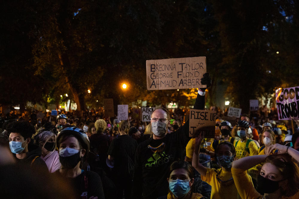 A man holds a sign with the names of Breonna Taylor, George Floyd and Ahmaud Arbery in Portland on Saturday.