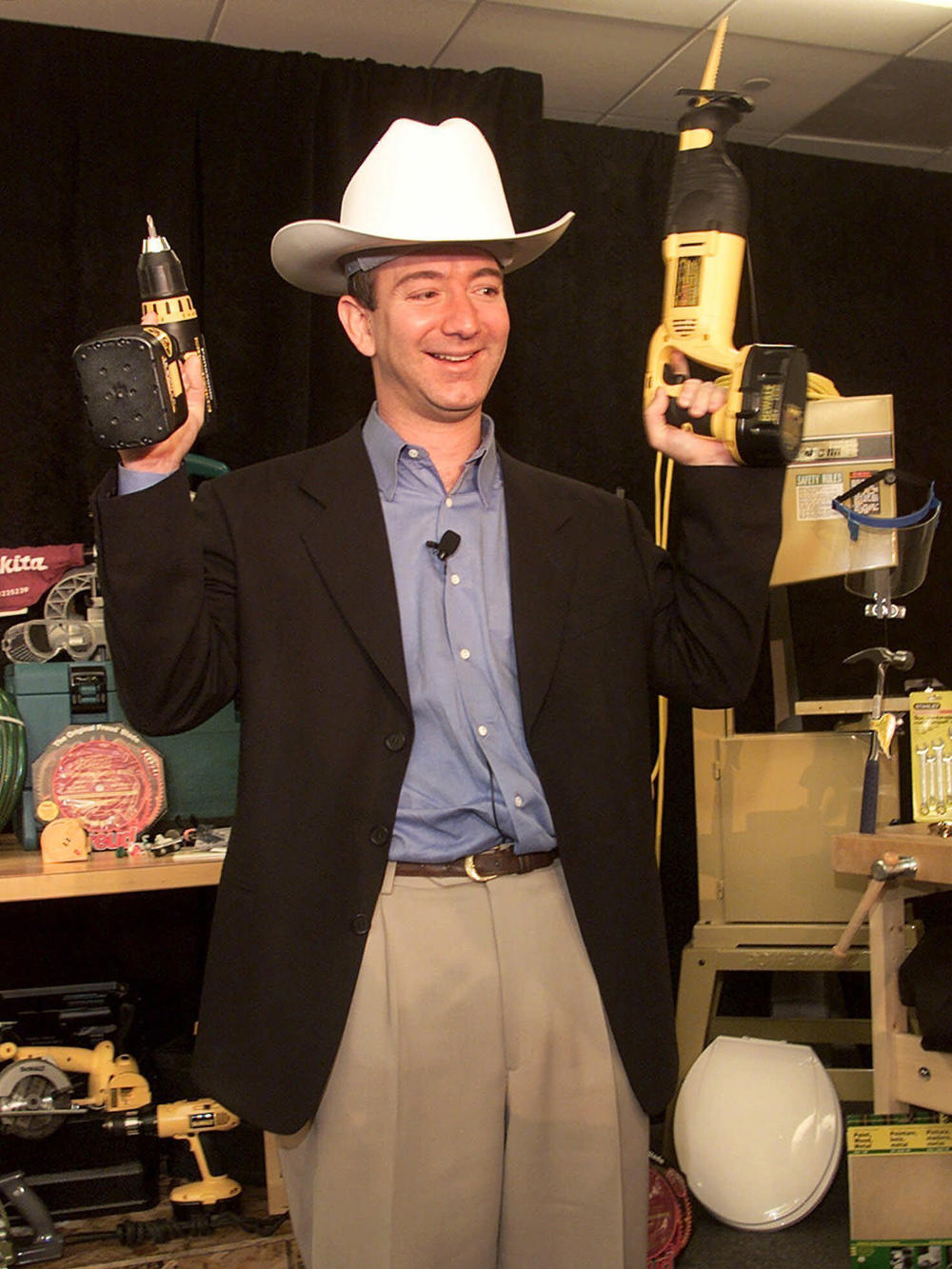 With Amazon expanding its selection, Bezos poses with a power drill and reciprocating saw in a Western-style hard hat at a 1999 news conference in New York.
