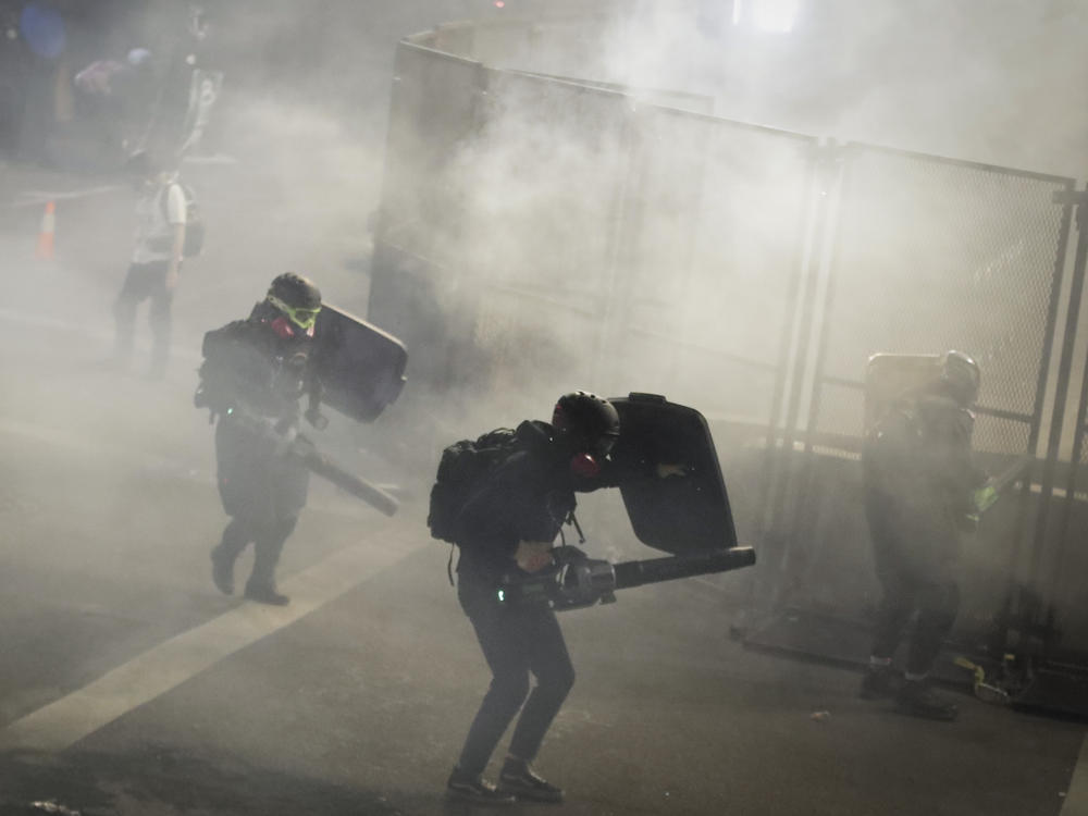 Demonstrators use leaf blowers to try to blow back tear gas launched by federal officers during a Black Lives Matter protest at the Mark O. Hatfield United States Courthouse on Sunday in Portland, Ore.
