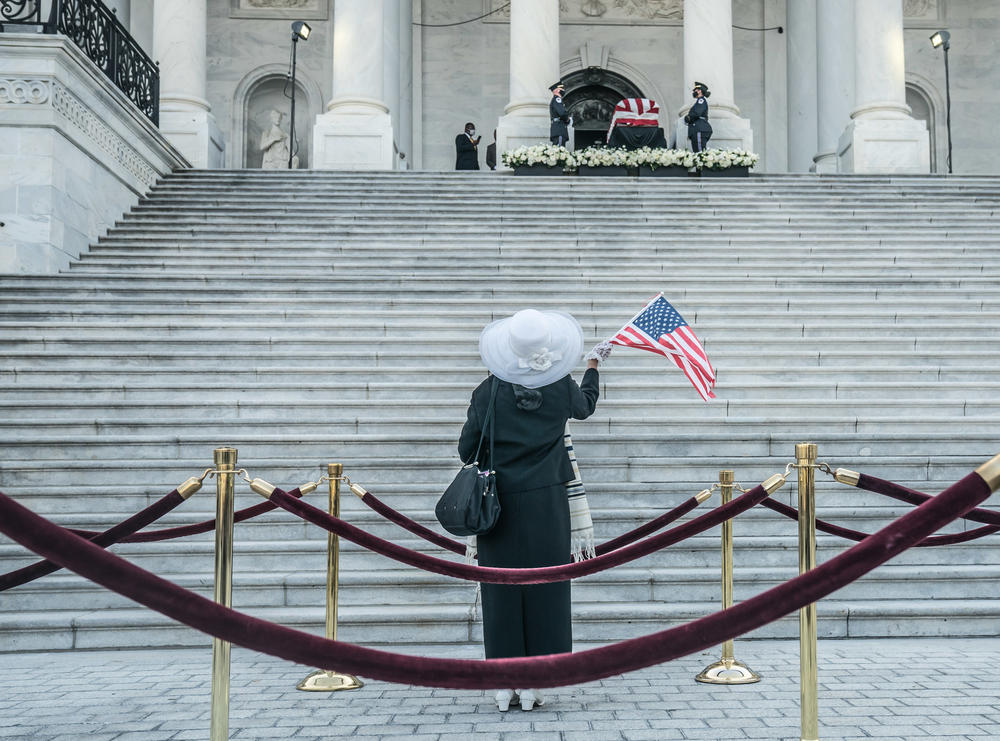 A mourner waves a flag as Rep. John Lewis (D-GA) remains are bought out for the public viewing.