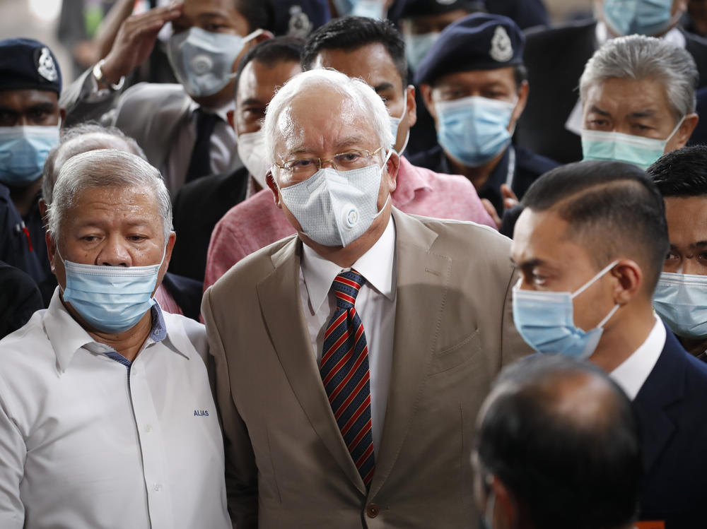 Former Malaysian Prime Minister Najib Razak (center), wearing a face mask with his supporters, arrives at the courthouse in Kuala Lumpur, Malaysia, on Tuesday. Najib was found guilty of corruption in the first of several trials linked to the multibillion-dollar looting of the 1MDB state investment fund.