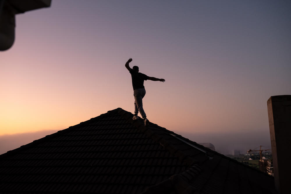 Zip Zap perfomer Jason Barnard climbs on a rooftop near his home in Green Point, Cape Town, South Africa. He's best known for his juggling skills and clown act and also works as an instructor.