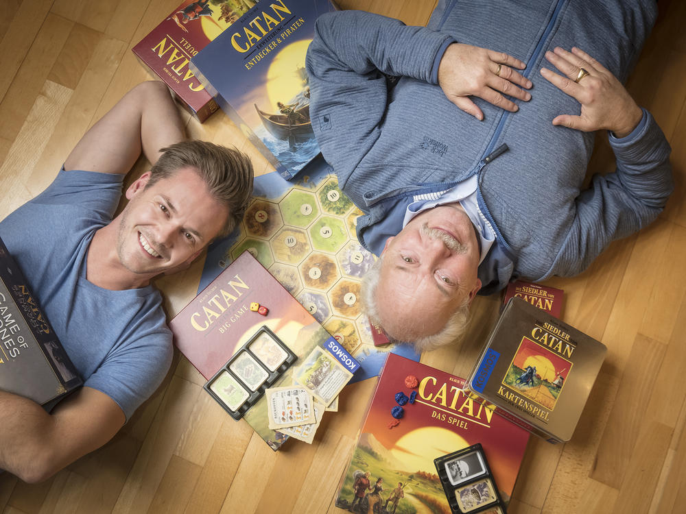Klaus Teuber, creator of the popular board game Catan, with his son Benjamin Teuber, a managing director at Catan Inc. Celebrating the 25th anniversary of the game's launch, the elder Teuber has released an autobiography, <em>My Way to Catan</em>.