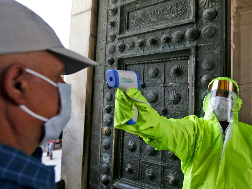 A medic checks the temperature of a Syrian worshipper before entering the Umayyad Mosque in Damascus to attend Friday prayer on May 15. To try to slow the coronavirus outbreak, the Syrian government has banned mass prayers and asked Syrians to stay home over the Muslim holiday of Eid al-Adha this weekend.