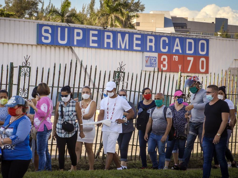 People wait to buy products with U.S. dollars at a supermarket in Havana on July 20. Cuba has eliminated a tax on dollars and opened 