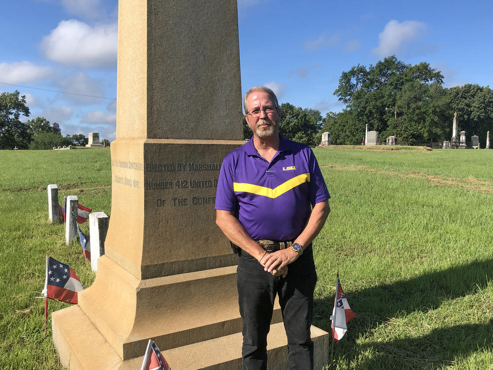 Bill Elliott, local commander of the Sons of Confederate Veterans, stands before an obelisk honoring unknown Confederate soldiers buried in the city cemetery. Some locals suggest the soldier statue should be moved to the cemetery.