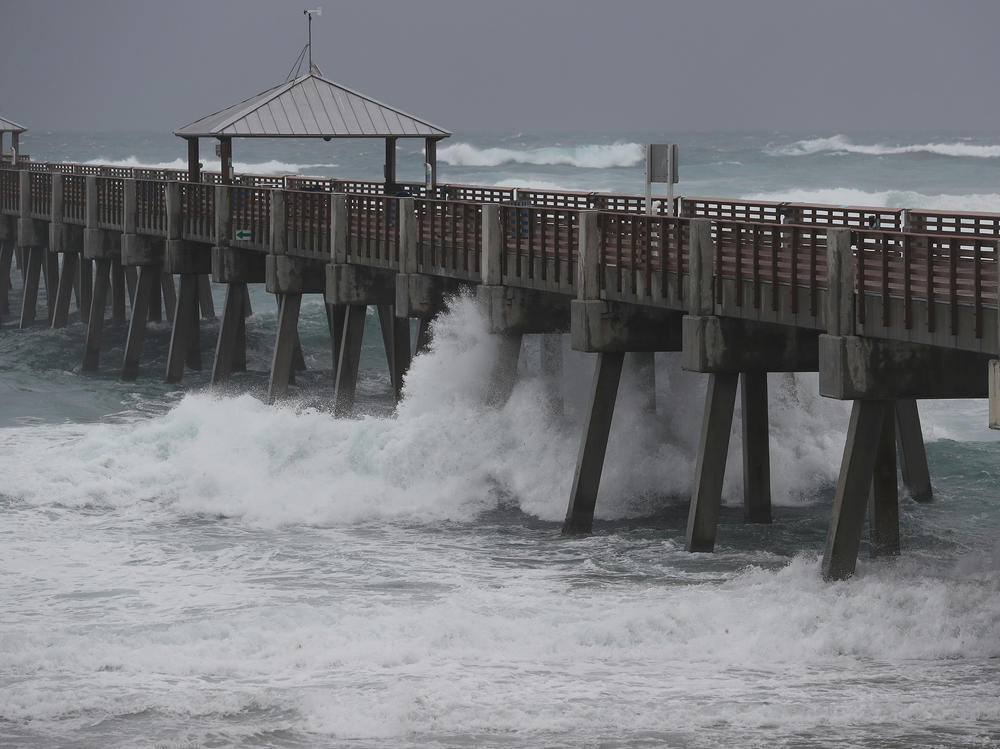 Waves crash along the Juno Beach Pier as Tropical Storm Isaias passes through the area Sunday in Juno Beach, Fla. The storm is now headed toward the Carolinas.