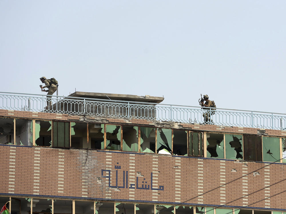 Afghan security personnel take position on the top of a building where insurgents were hiding in the city of Jalalabad, Afghanistan, on Monday. The day before, militants attacked a prison holding many ISIS members.