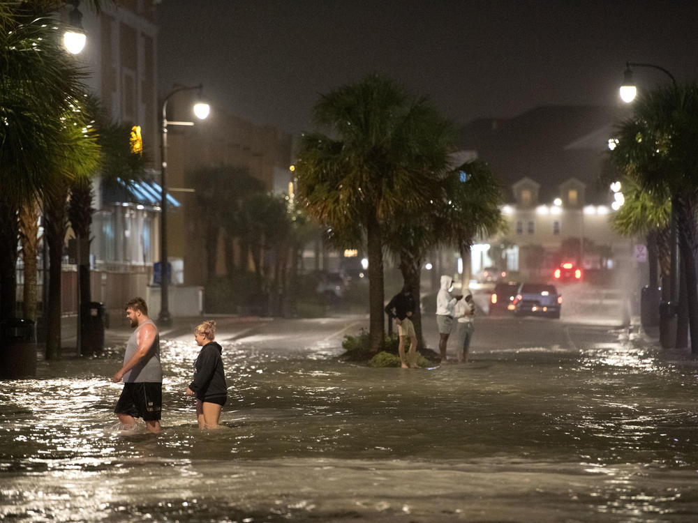 Hurricane Isaias made landfall near Ocean Isle Beach, N.C., near the border with South Carolina. Pictured are people walking through floodwaters in Myrtle Beach, S.C.