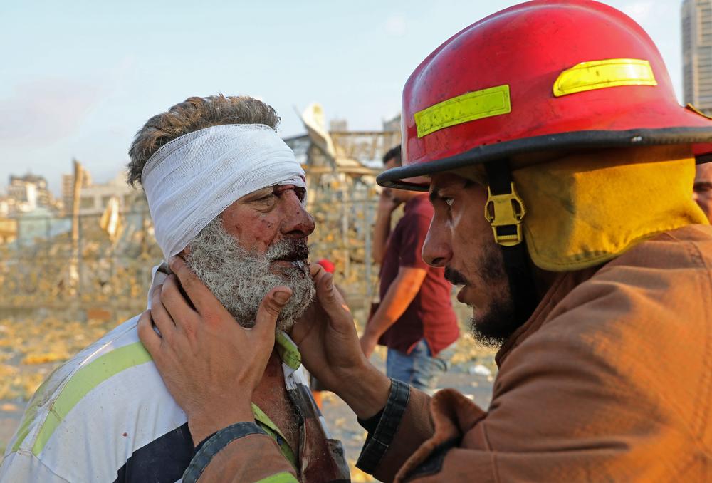 A firefighter checks a wounded man near the scene of the explosion in Beirut.