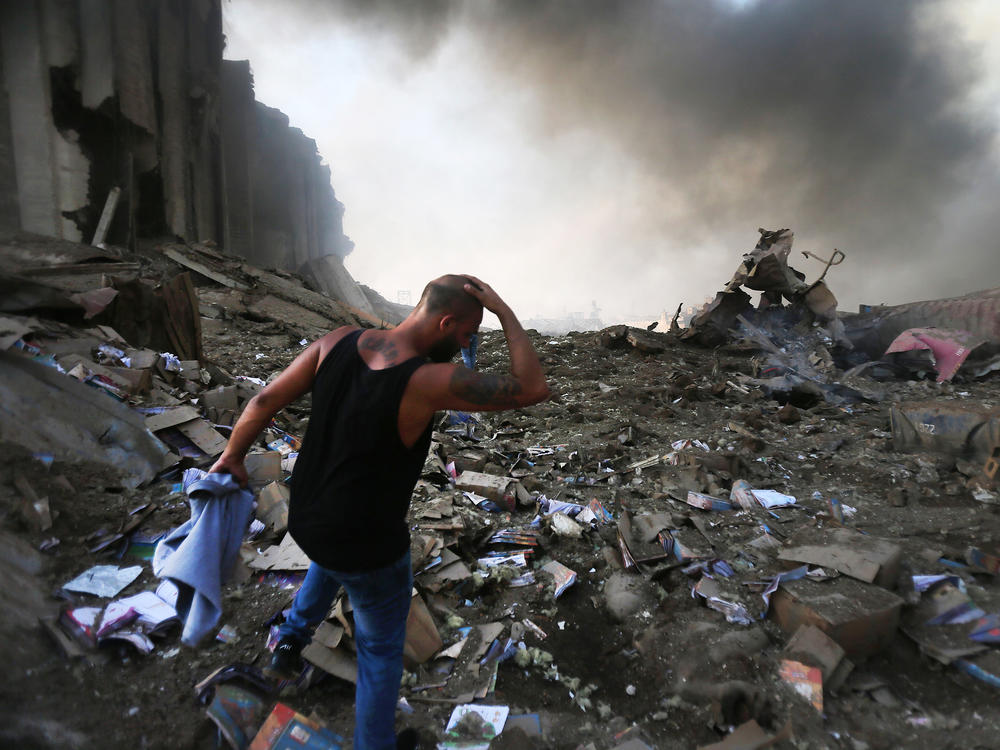 A man walks through debris near the scene of the enormous explosion in Lebanon on Tuesday. At least 70 people were killed, and at least 2,700 people were hurt. The blast shattered windows and damaged buildings across a wide swath of Beirut.