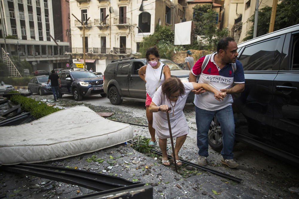 A woman is assisted while walking through debris after Tuesday's explosion in Beirut.