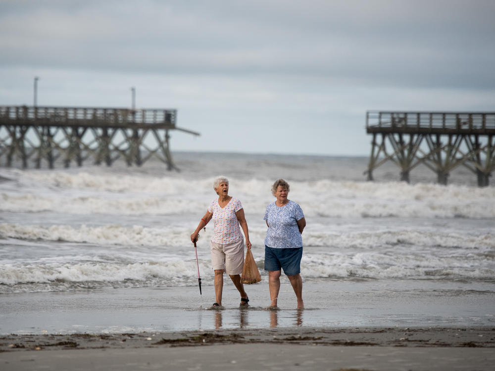 Mary McCants (left) and Amy Garrett walk near a damaged pier the morning after Hurricane Isaias came through late Monday night in North Myrtle Beach, S.C. Hurricane Isaias was downgraded to a tropical storm on Tuesday after making landfall overnight as a Category 1 hurricane.