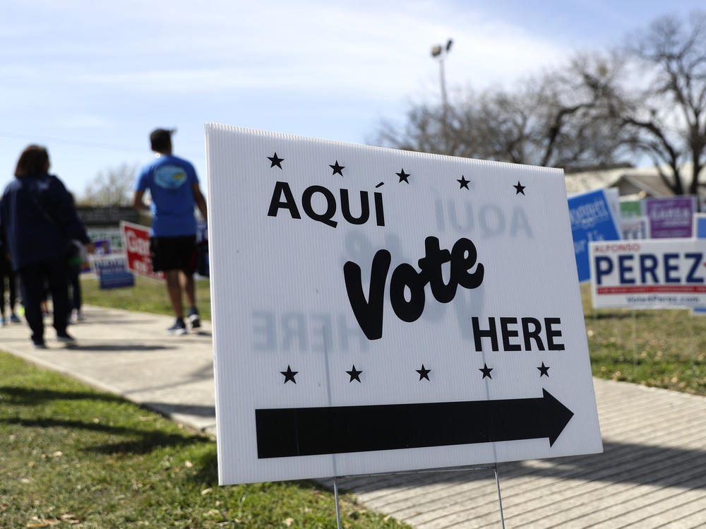 Pedestrians pass signs near a polling site in San Antonio in February.