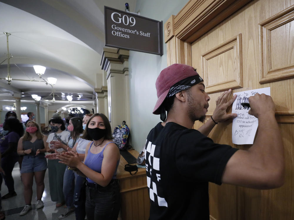 Matthew Bruce of Des Moines, Iowa, signs a note during a Black Lives Matter demonstration outside Iowa Gov. Kim Reynolds' office in June. The Republican governor has signed an executive order restoring voting rights to people convicted of a felony.