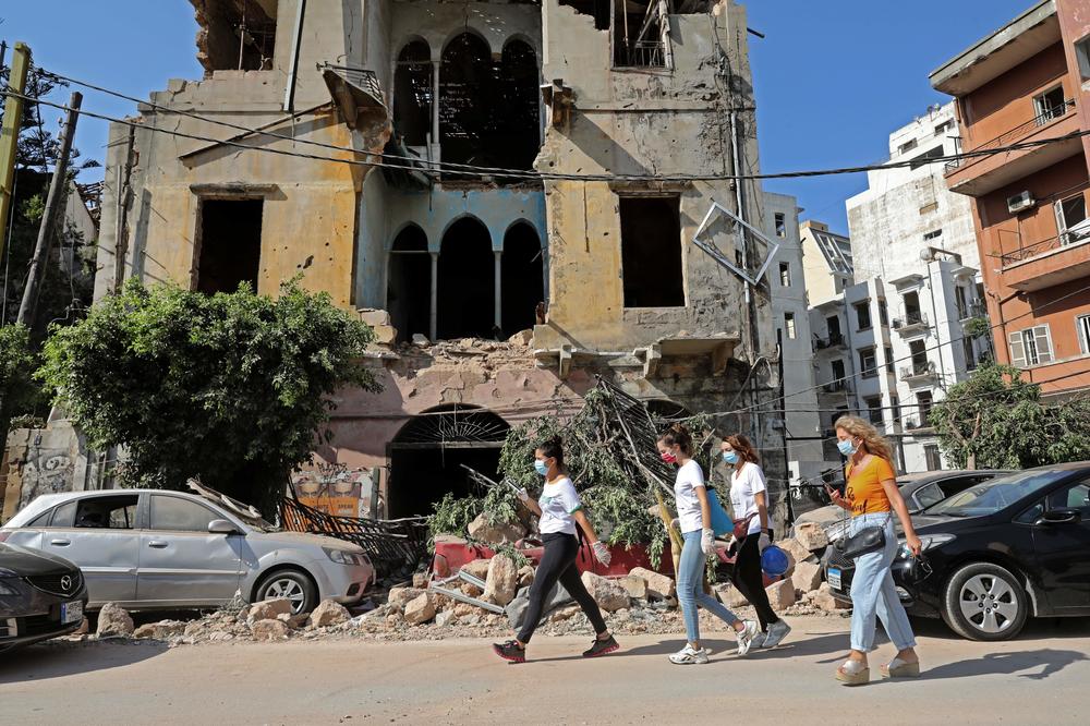 Women walk past a damaged building Wednesday in the aftermath of the blast that tore through Lebanon's capital. Rescuers continue to search for the missing.