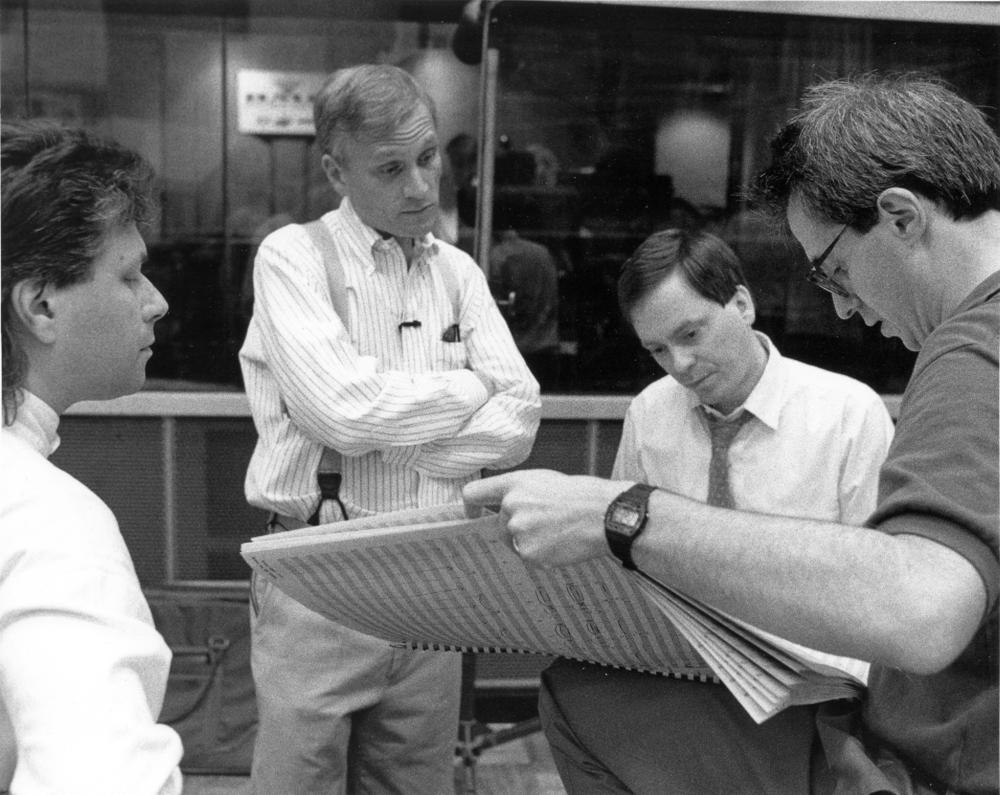 Composer Alan Menken (far left) and lyricist Howard Ashman (center-left) review a score with producer Don Hahn (far right).