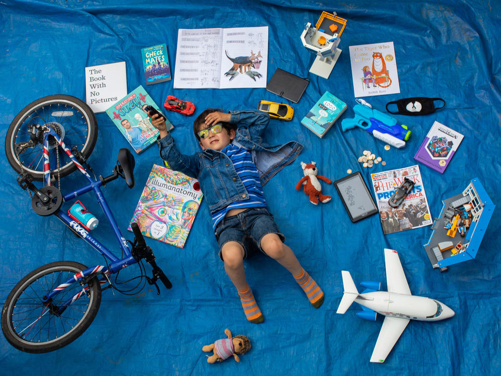 Elizabeth Dalziel's son Joe, 7, lays next to his favorite objects, toys and books as part of a homeschooling assignment — to create a time capsule — from his school in Berkhamsted, England.