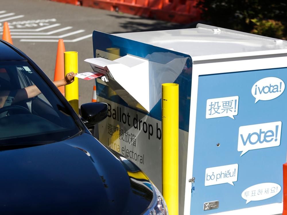 A voter inserts a ballot in a drive-up drop box last week in Renton, Wash., in that state's primary. With more states expanding absentee voting due to the pandemic, the use of drop boxes is growing and leading to legal challenges from some Republicans.