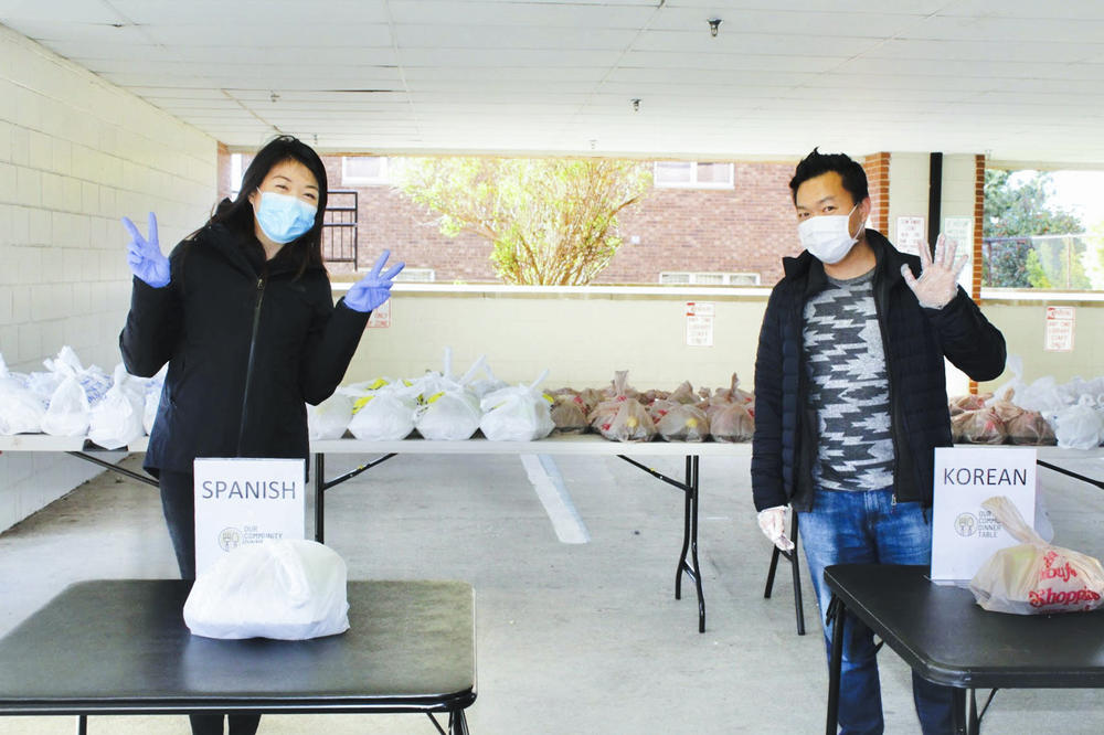 Volunteers Soojung Kwak and Pastor Bob Koo prepare to distribute meals for Our Community Dinner Table.
