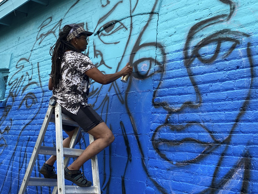 Artist Marsha Hatcher spray-paints an outline for a Black Votes Matter mural, a project supported by Color Jax Blue, in Jacksonville, Fla.