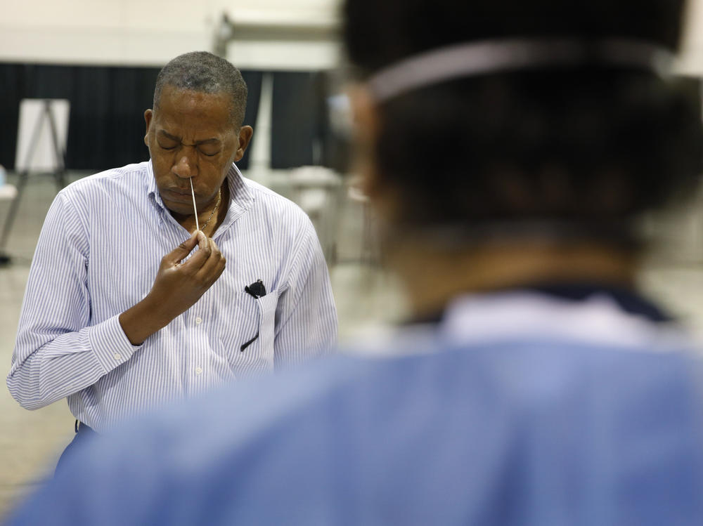 Clark County Commission Vice Chairman Lawrence Weekly swabs his nose while giving a coronavirus test to himself during a tour of setup at a temporary coronavirus testing site in Las Vegas on Aug. 3.