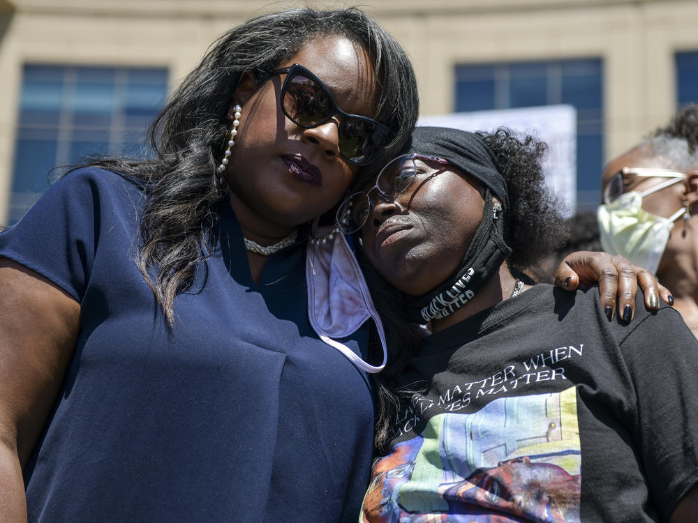 Elijah McClain's mother, Sheneen McClain (right), gets a hug from <strong></strong>Colorado state Rep. Leslie Herod in June as they stand with protesters outside the Aurora, Colo., police headquarters. On Tuesday, Sheneen McClain and Lawayne Mosley filed a federal civil rights lawsuit in their son's death.