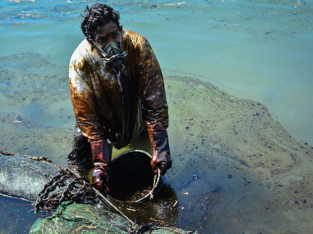 A man scoops oil from the coast of Mauritius on Saturday. A Japanese cargo ship ran aground near Blue Bay Marine Park in late July and began to leak fuel oil and diesel into pristine waters.