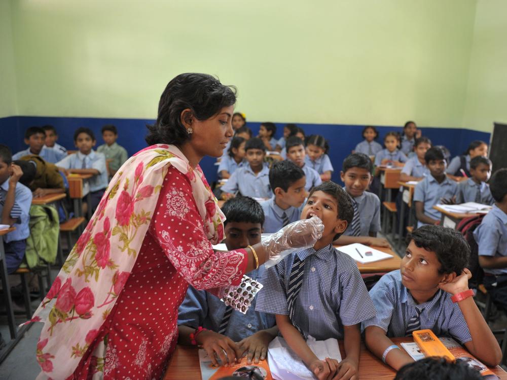 A teacher gives a deworming tablet to a student during National Deworming Day at a high school in Hyderabad, India, in 2017.