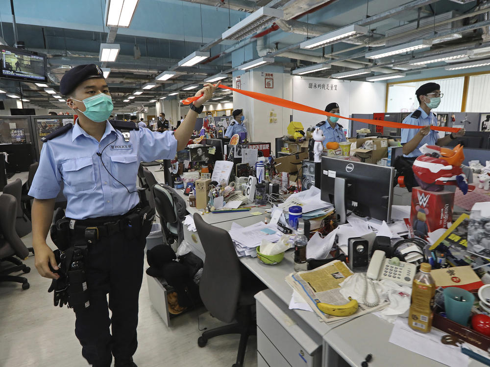 Hong Kong police officers search the newsroom of the <em>Apple Daily</em> newspaper Monday after arresting the paper's publisher, Jimmy Lai.
