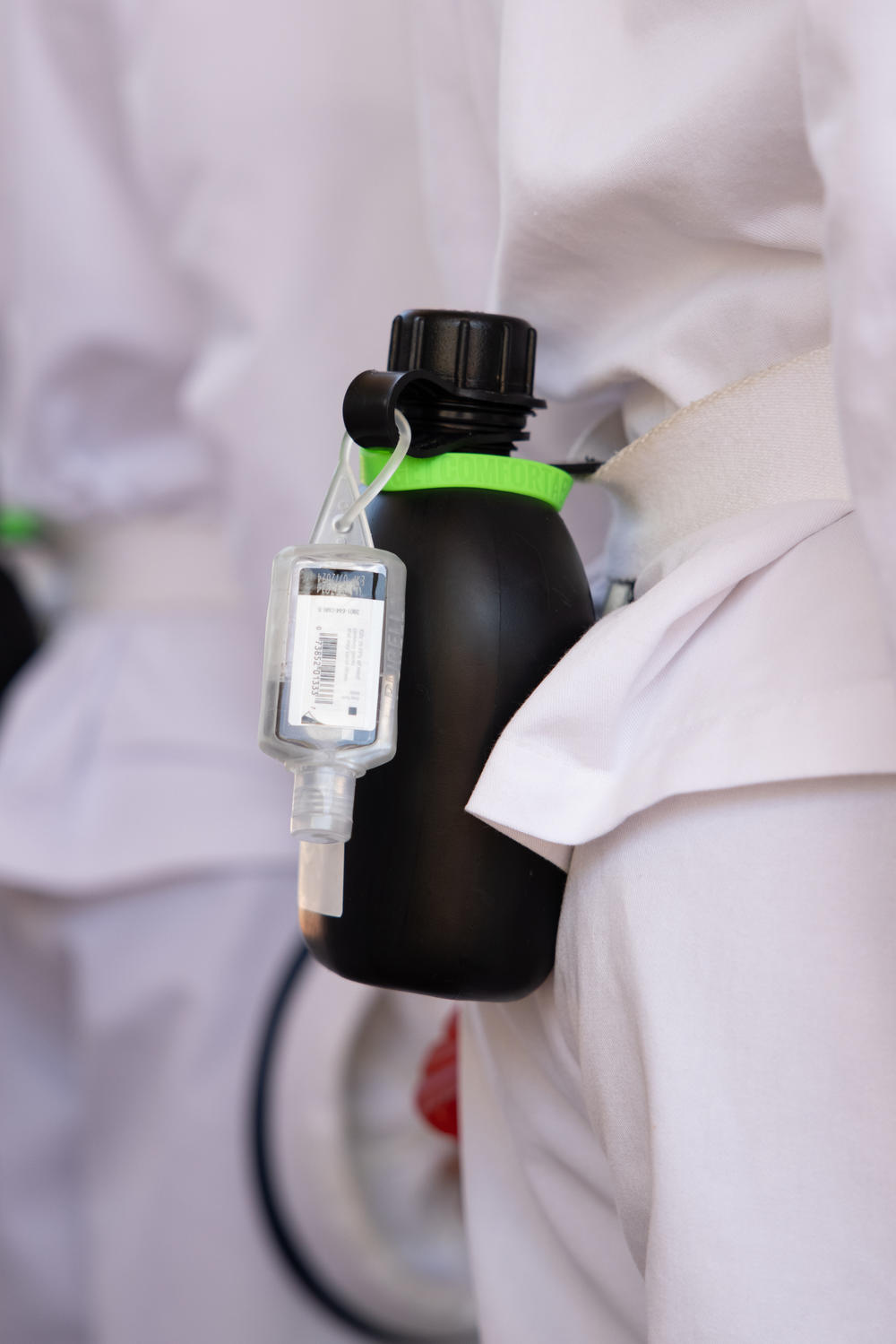 A bottle of hand sanitizer is attached to a water canteen on a freshman's belt.