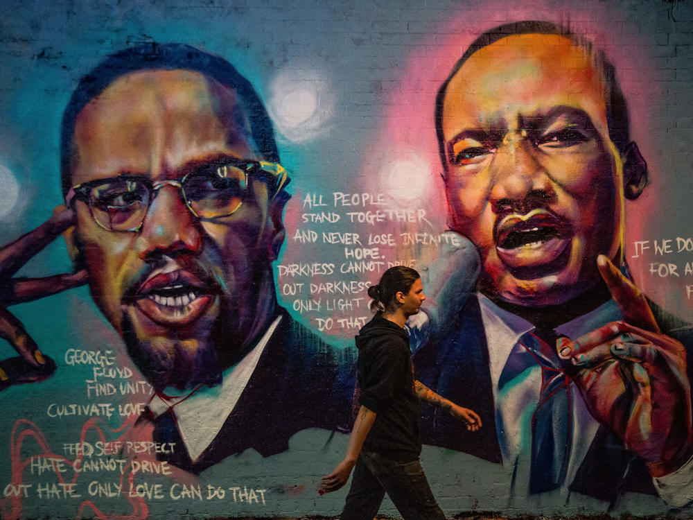 A man walks past a mural of Malcom X and Martin Luther King Jr. in London.