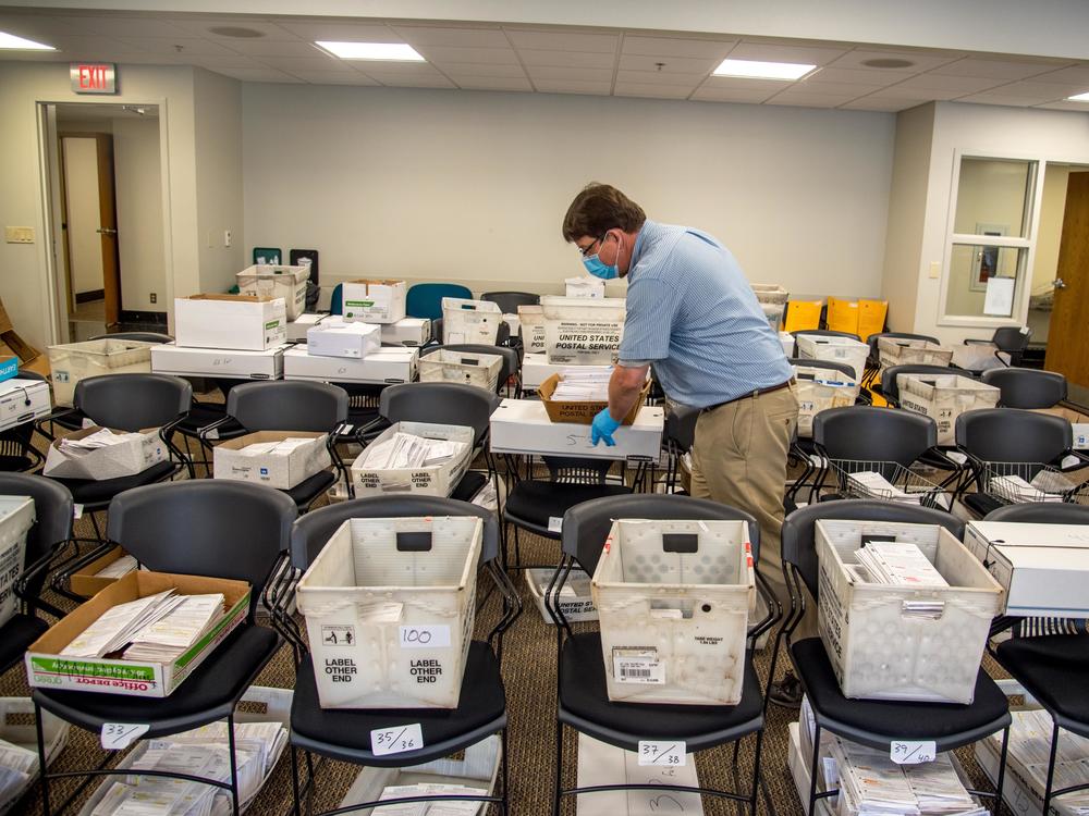 Election official Jim Fortner places a crate of sorted absentee ballots with others from the same ward at the Madison, Wis., City-County Building on Aug. 5, 2020. Delays and failure to deliver absentee ballots in Wisconsin and other key swing states have sparked concerns about how well the November presidential election will be managed during the pandemic.