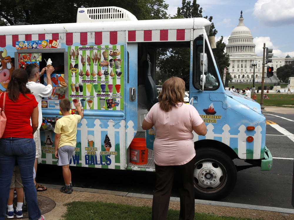 With the U.S. Capitol as a backdrop, tourists wait in line to get ice cream from a food truck on the National Mall in Washington.