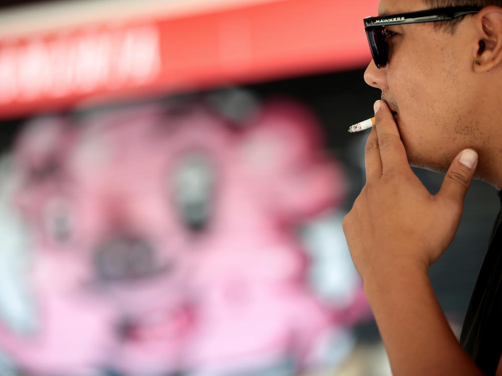 A man smokes in the street in Madrid on Friday after Spain's health minister announced curbs on smoking outdoors in an effort to contain a resurgence of COVID-19.
