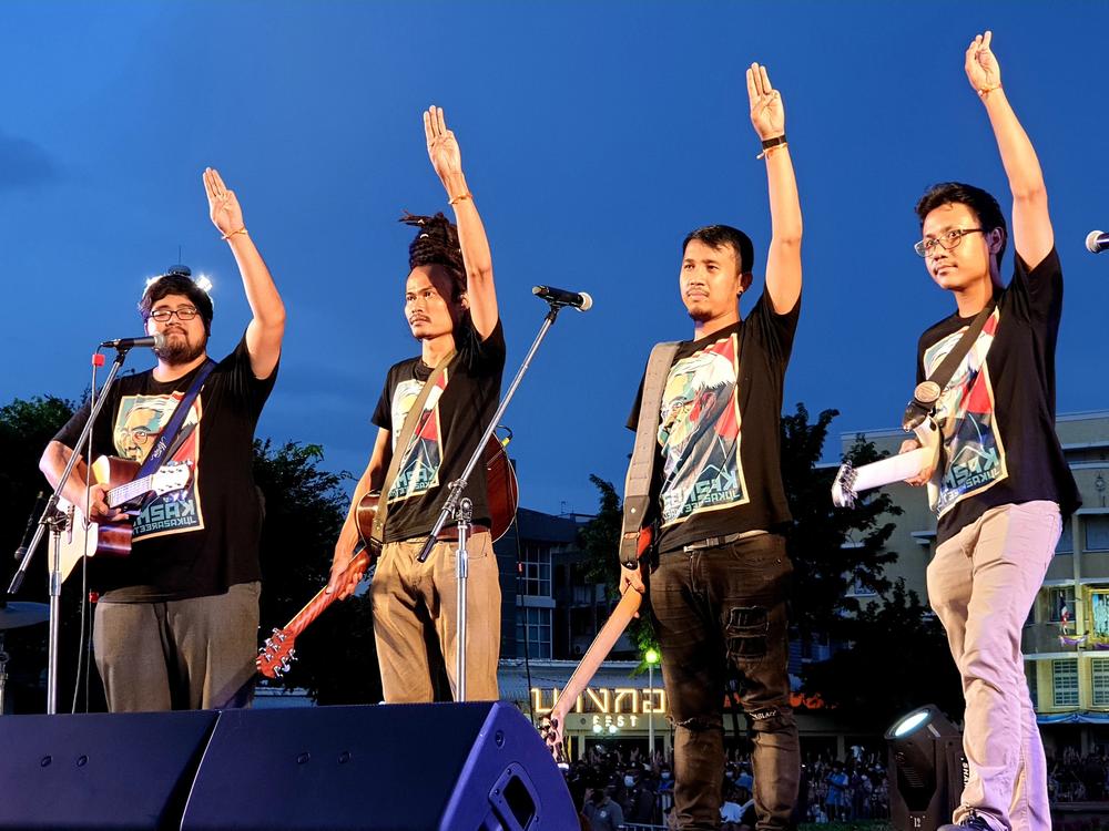 Members of a musical group at Sunday's pro-democracy demonstration in Bangkok make a gesture of resistance popularized by <em>The</em> <em>Hunger Games </em>movies.