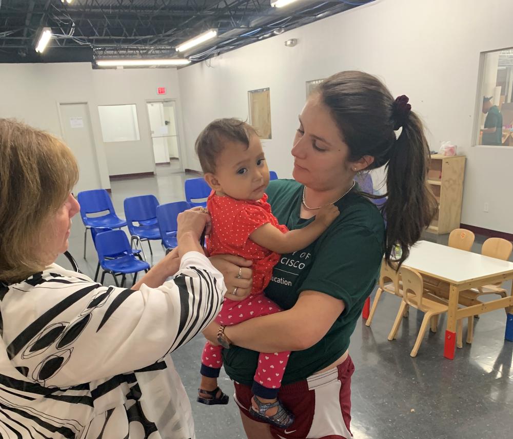 Dr. Goza listens to the lungs of a 2-year-old at Catholic Charities' Humanitarian Respite Center in McAllen, TX. After the toddler was released from CBP, she was sent to the emergency room with pneumonia and an undiagnosed congenital heart condition.