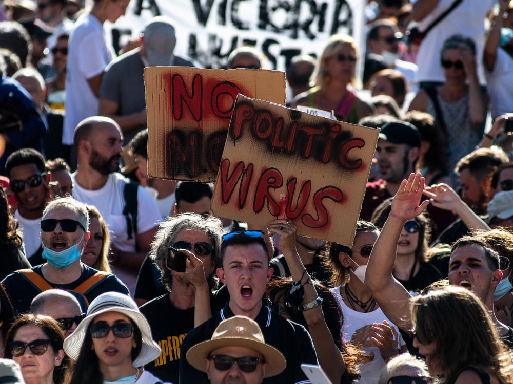People holding placards and shouting slogans protest Sunday in Madrid against the mandatory use of face masks and other measures adopted by the Spanish government to prevent the spread of the coronavirus.