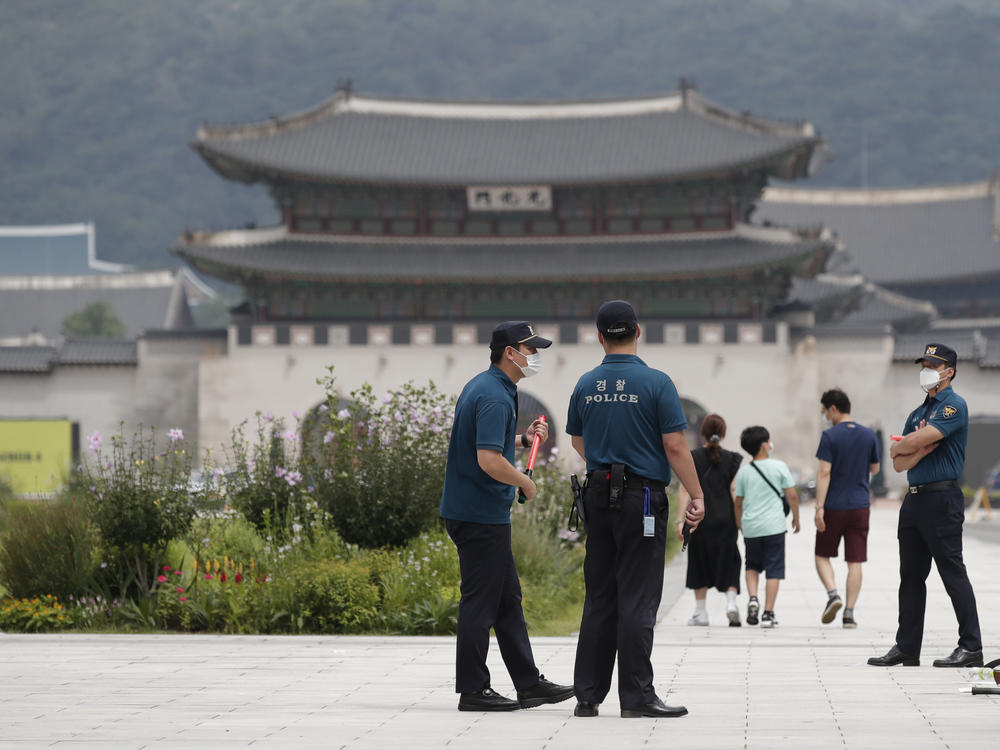 Police officers and visitors wearing face masks to help protect against the spread of the coronavirus walk in downtown Seoul, South Korea, on Sunday.