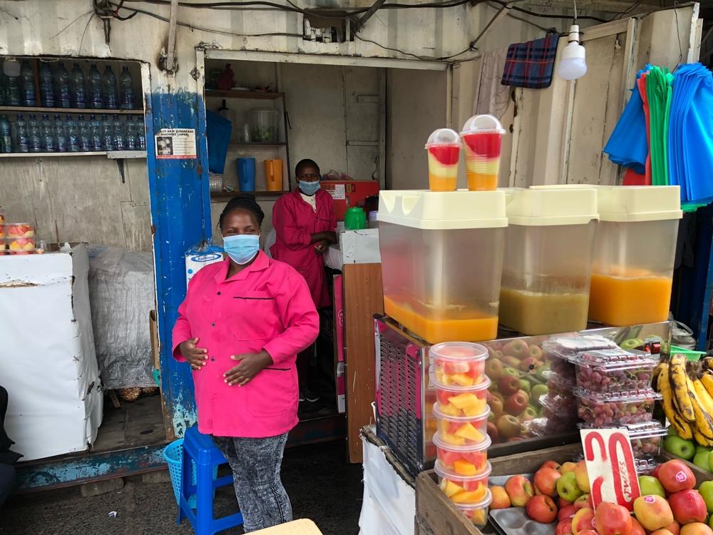 Muthuma stands next to fountains of dawa at her fruit and vegetable stand in Nairobi, Kenya.