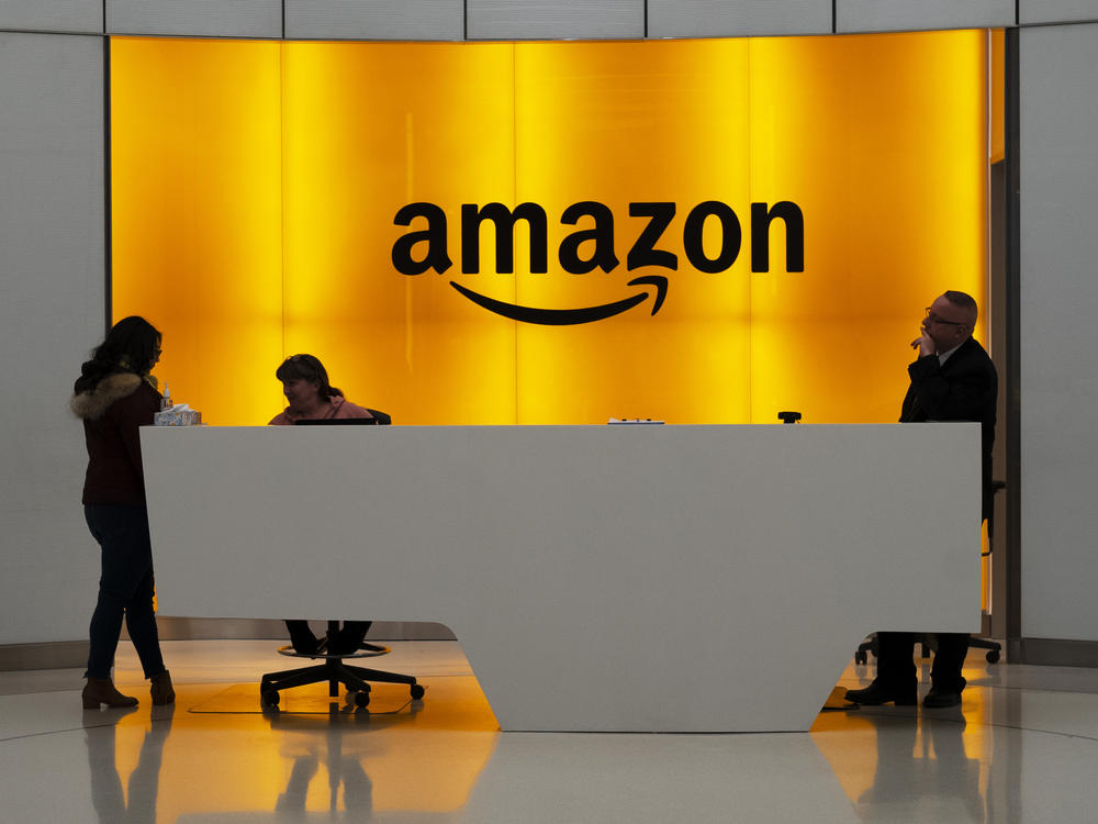 People stand in the lobby of Amazon offices in New York in January 2019. At a time of mass work from home and many moving to spacious suburbs, Amazon is funding a large expansion of corporate real estate and jobs in New York and five other U.S. cities.