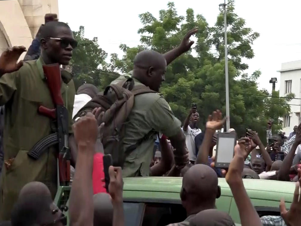 In a screen grab captured from a video, soldiers on a military vehicle are greeted by citizens Tuesday at Independence Square in Bamako, Mali. Soldiers staged a mutiny, and reportedly detained President Ibrahim Boubacar Keita.