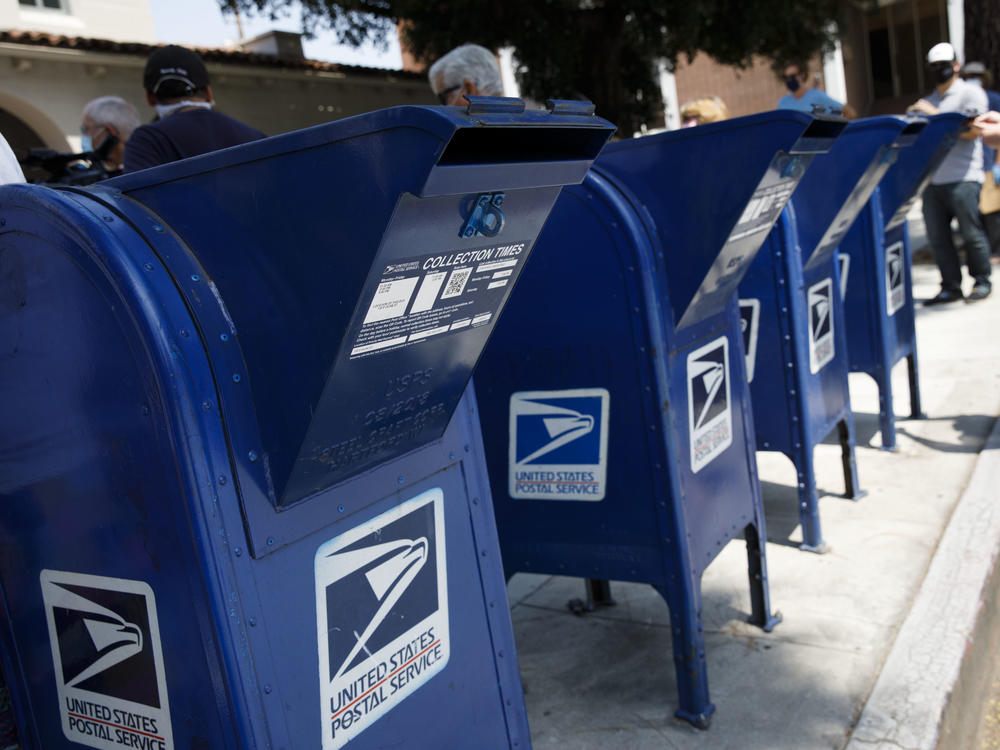 A customer deposits mail into a U.S. Postal Service mail collection box this week in Burbank, Calif.