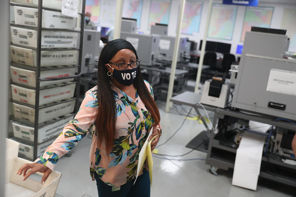 Workers at the Miami-Dade County Elections Department work on tabulating mail-in ballots Tuesday in Doral, Fla.