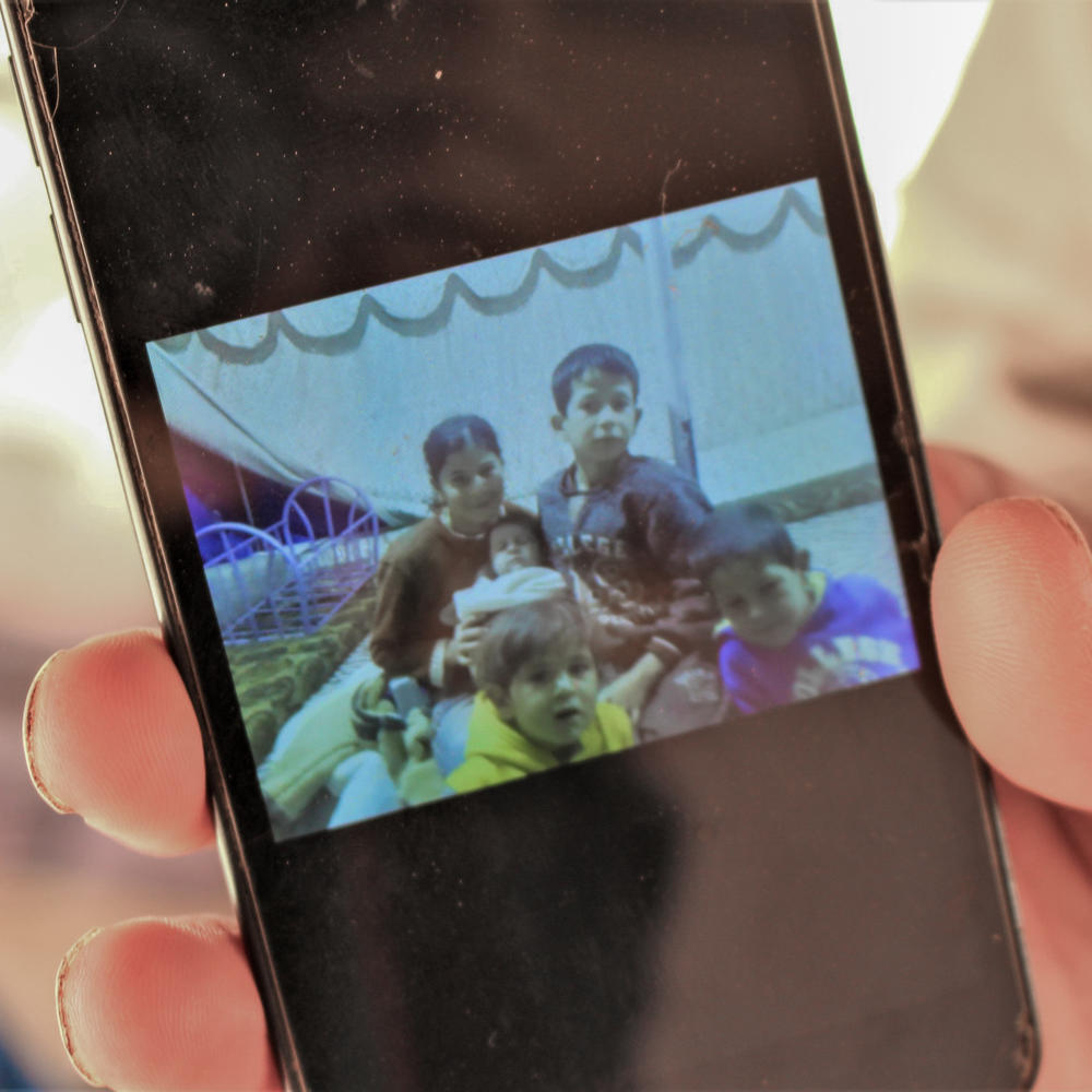 Mohammad al-Saleh holds his phone showing a photo of his children who burned to death in a tent fire in June. His eldest daughter, also in the photo, was not in the tent and is one of the family's two surviving children.