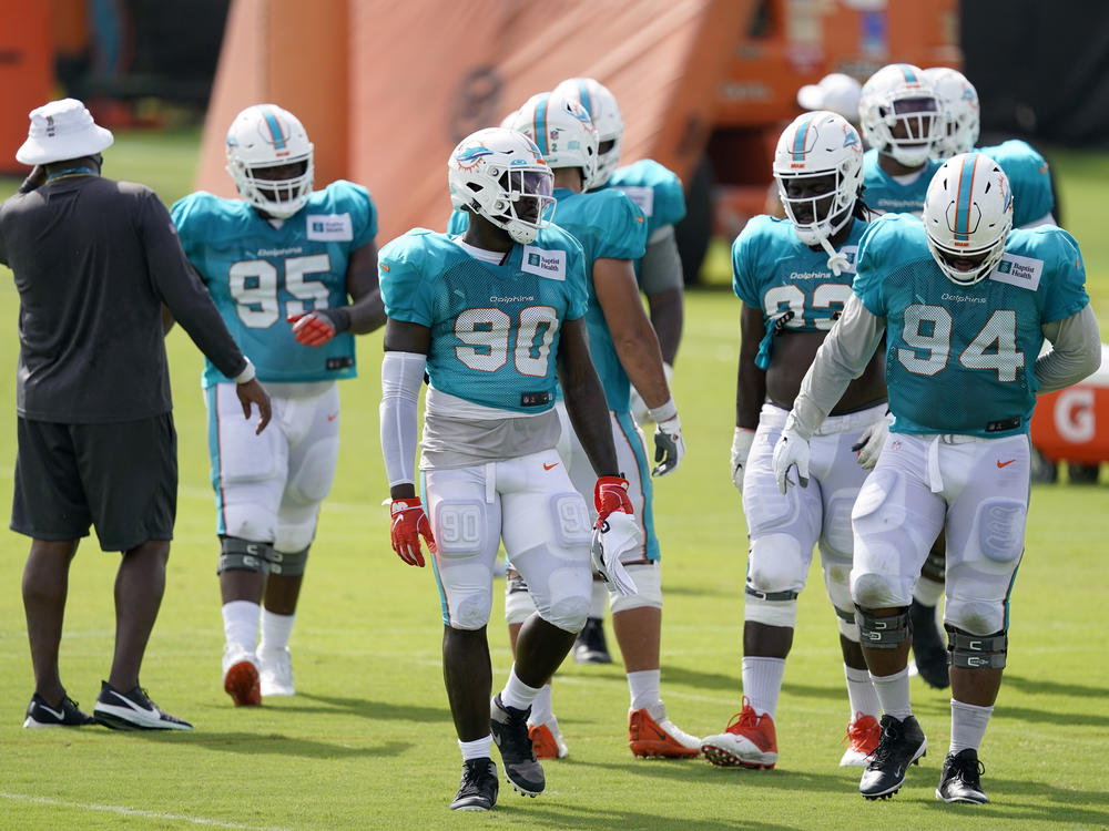 Players for the Miami Dolphins take a break between practice drills during training camp last Friday. When the regular season begins, they'll be playing in front of a smaller-than-normal crowd due to coronavirus restrictions.