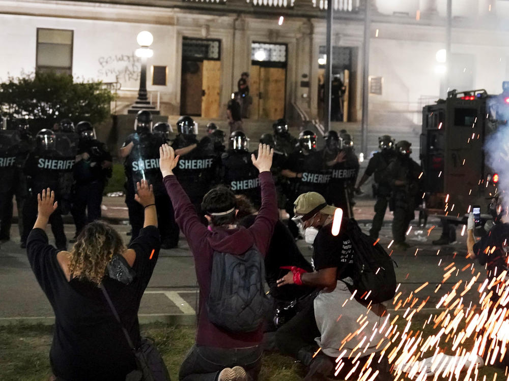 Police attempt to push back protesters outside the Kenosha County Courthouse late Monday in Kenosha, Wis. Protests continued for a second night after the police shooting of Jacob Blake.