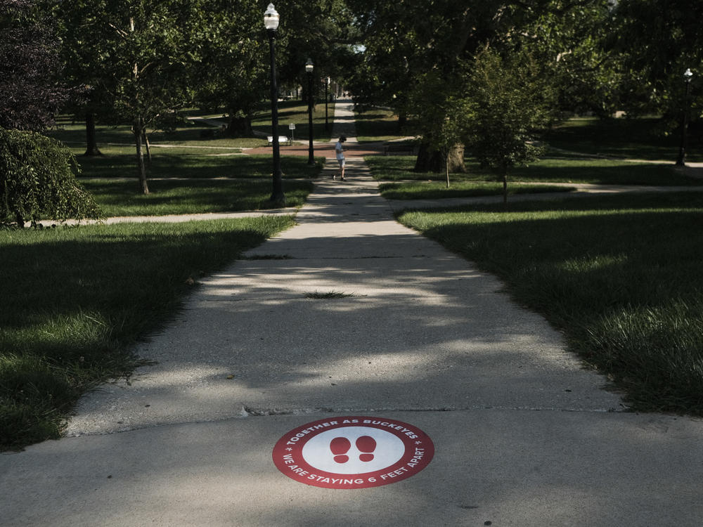 A sign on the ground at The Ohio State University reminds students to practice social distancing. The university has issued more than 200 interim suspensions to students linked to off-campus parties.